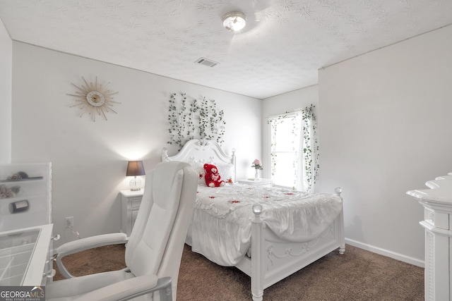 bedroom with a textured ceiling and dark colored carpet