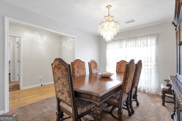 dining space with carpet floors, a textured ceiling, and a notable chandelier