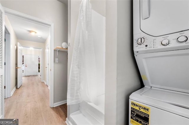 laundry room featuring stacked washer and dryer and light hardwood / wood-style flooring