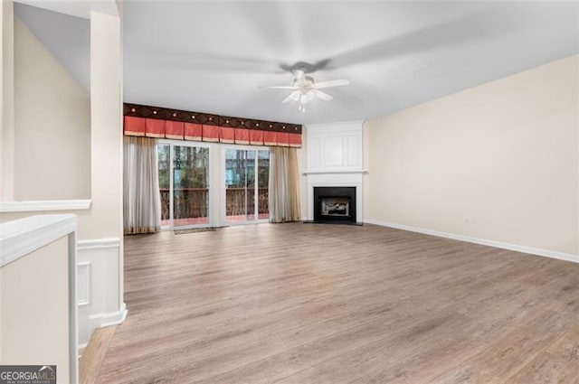 unfurnished living room featuring a large fireplace, hardwood / wood-style floors, and ceiling fan