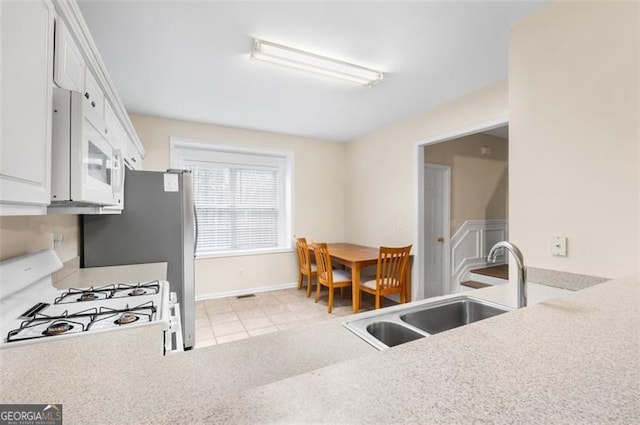 kitchen featuring white cabinetry, white appliances, light tile patterned flooring, and sink