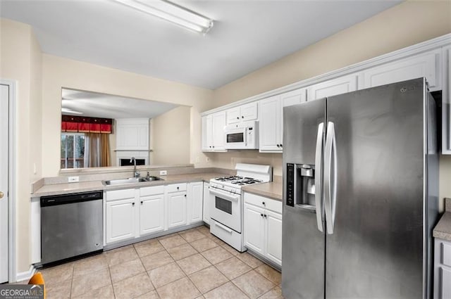 kitchen with white cabinetry, sink, light tile patterned floors, and stainless steel appliances