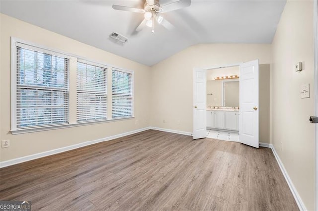 unfurnished bedroom with vaulted ceiling, wood-type flooring, ceiling fan, and ensuite bath