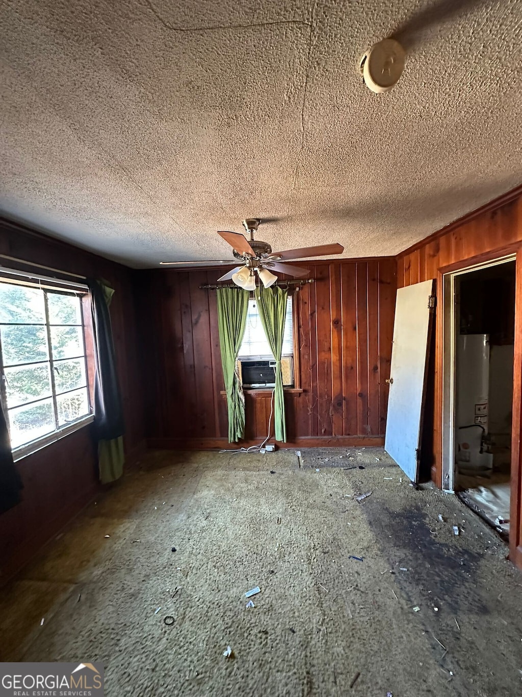 interior space with crown molding, water heater, a textured ceiling, and wood walls