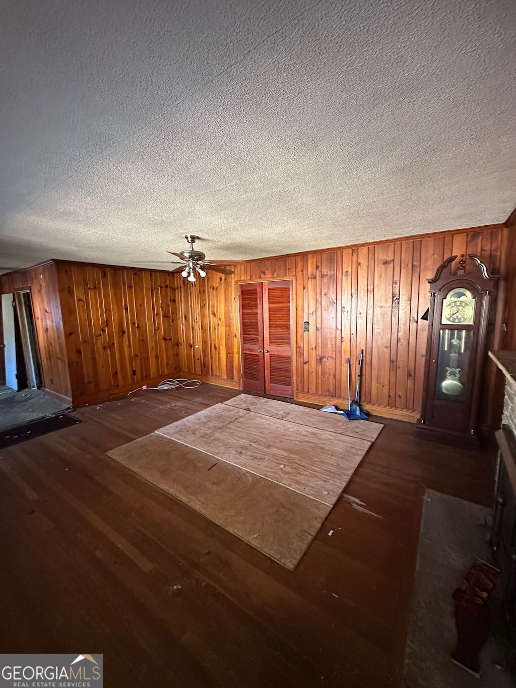 interior space featuring wood walls, a textured ceiling, dark hardwood / wood-style flooring, ceiling fan, and a fireplace