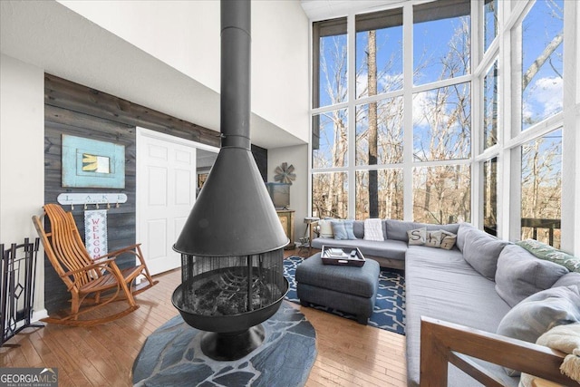 living room featuring a wall of windows, hardwood / wood-style floors, a high ceiling, and a wood stove