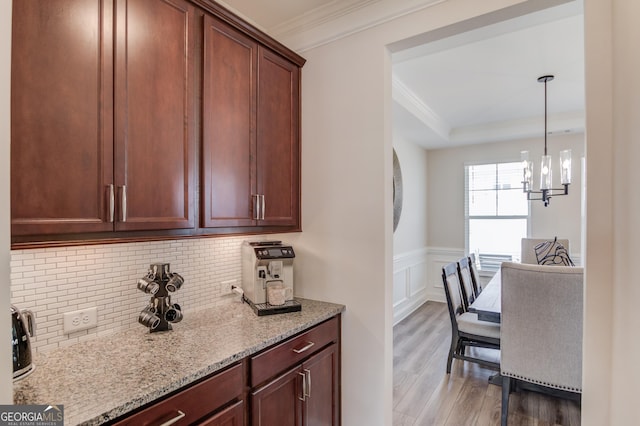 kitchen with ornamental molding, light hardwood / wood-style floors, light stone countertops, and backsplash