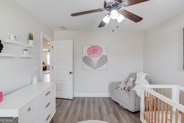 bedroom with ceiling fan, light wood-type flooring, and a nursery area