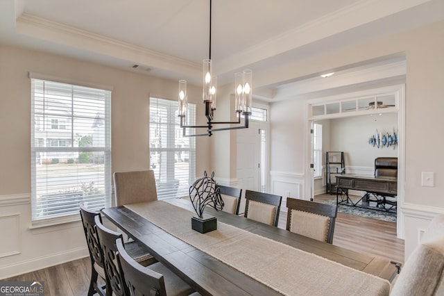 dining area featuring a tray ceiling, a chandelier, crown molding, and hardwood / wood-style floors