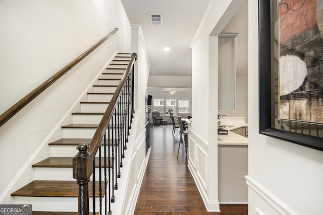 staircase featuring sink, wood-type flooring, ornamental molding, and ceiling fan