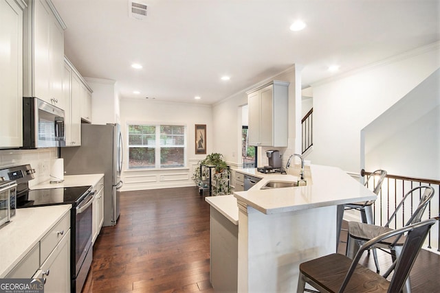 kitchen featuring sink, stainless steel appliances, a kitchen breakfast bar, dark hardwood / wood-style flooring, and kitchen peninsula