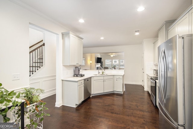 kitchen with sink, appliances with stainless steel finishes, white cabinetry, dark hardwood / wood-style flooring, and kitchen peninsula