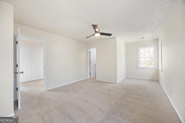 carpeted empty room featuring ceiling fan and a textured ceiling