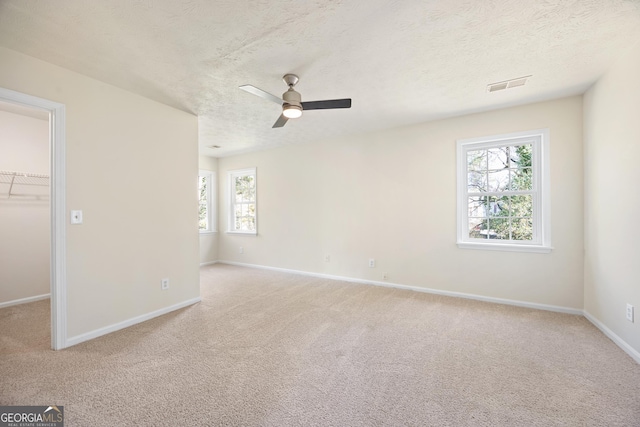 spare room with ceiling fan, light colored carpet, and a textured ceiling