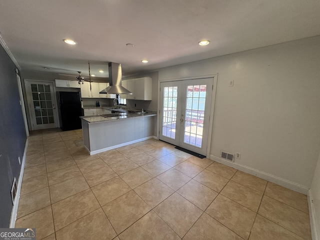 kitchen featuring french doors, island range hood, black refrigerator, kitchen peninsula, and white cabinets