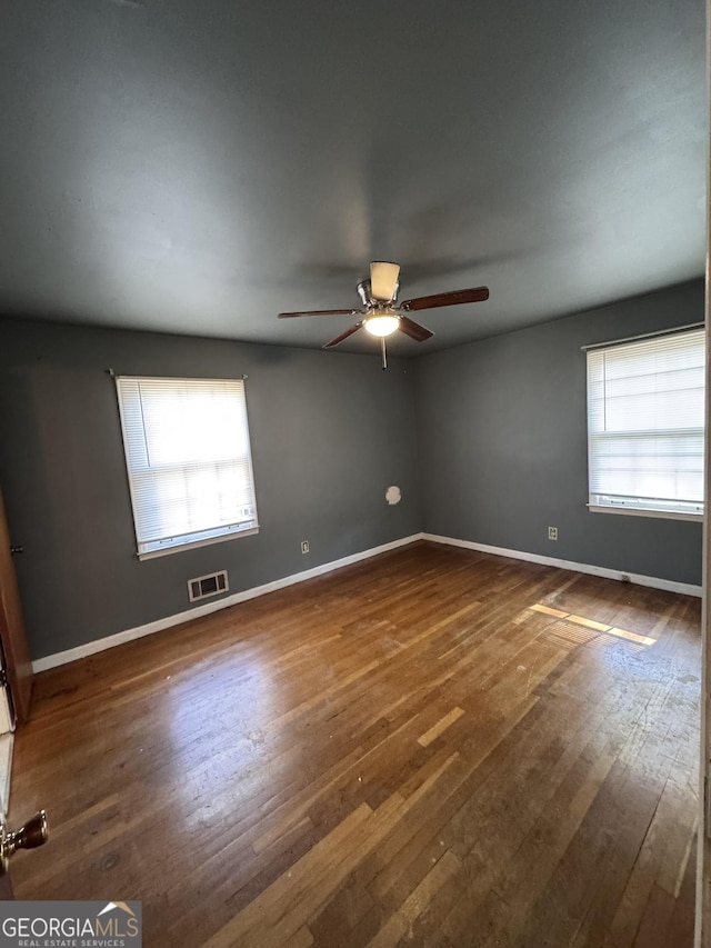 empty room with ceiling fan and dark hardwood / wood-style flooring