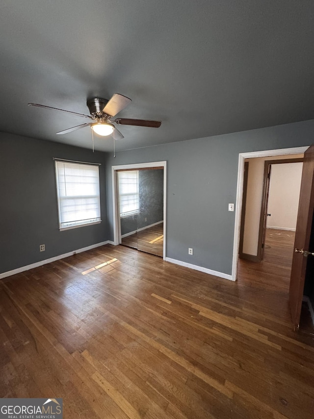 empty room with dark wood-type flooring and ceiling fan