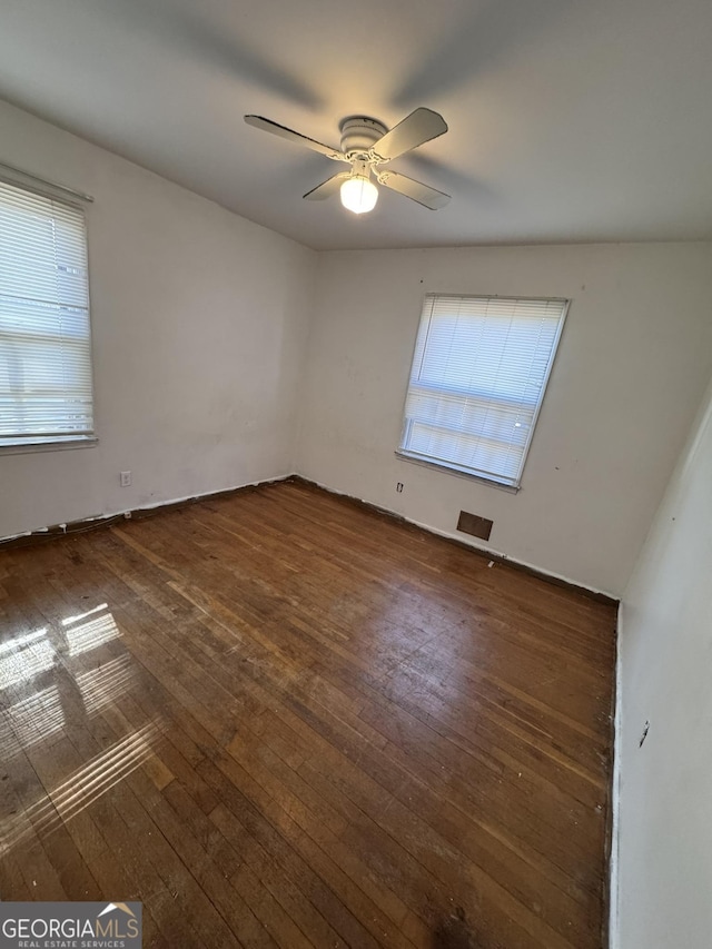 spare room featuring a wealth of natural light, dark hardwood / wood-style floors, and ceiling fan