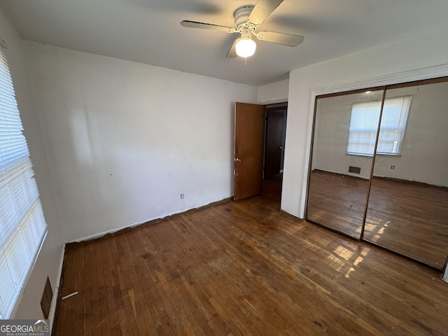 unfurnished bedroom featuring dark wood-type flooring, a closet, and ceiling fan