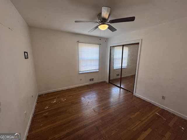 unfurnished bedroom with ceiling fan, dark hardwood / wood-style flooring, and a closet