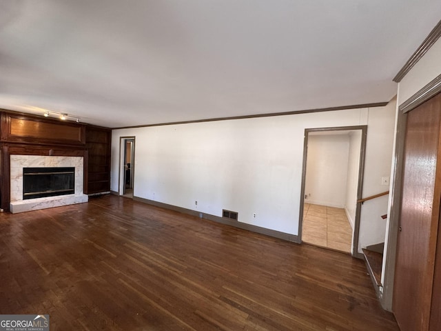 unfurnished living room featuring dark wood-type flooring, ornamental molding, and a fireplace