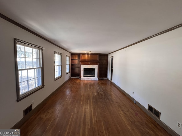 unfurnished living room with a premium fireplace, dark wood-type flooring, and crown molding