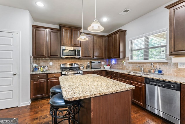 kitchen featuring dark brown cabinetry, sink, a center island, hanging light fixtures, and appliances with stainless steel finishes