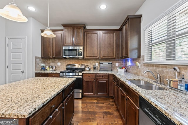 kitchen with stainless steel appliances, dark brown cabinets, sink, and pendant lighting