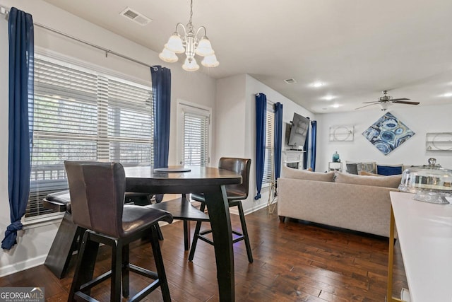 dining area with dark hardwood / wood-style floors and ceiling fan with notable chandelier