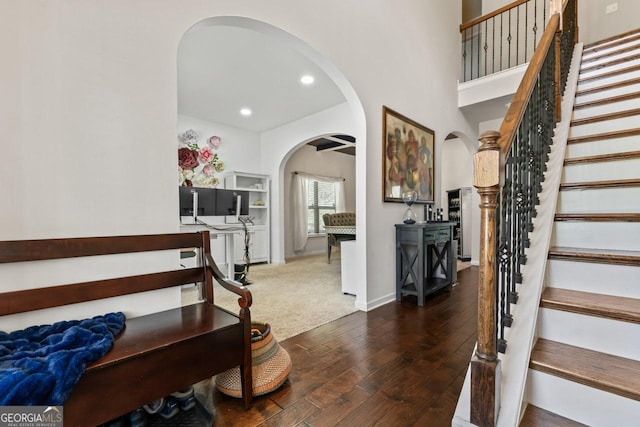 entryway with a towering ceiling and dark wood-type flooring