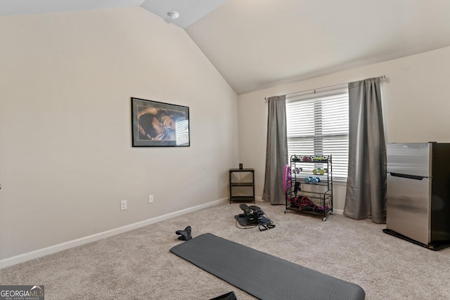 exercise area with lofted ceiling and light colored carpet