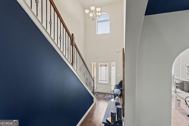 foyer featuring hardwood / wood-style flooring, plenty of natural light, a towering ceiling, and a chandelier