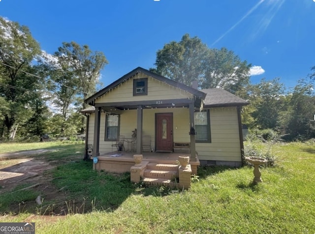 bungalow featuring covered porch and a front lawn