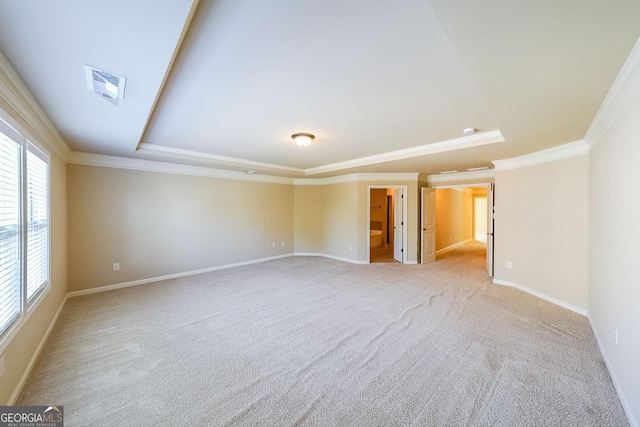 empty room with a raised ceiling, ornamental molding, and light carpet