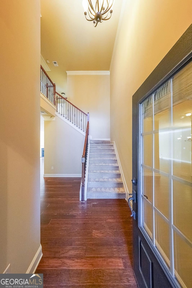 stairway featuring ornamental molding, wood-type flooring, and a chandelier