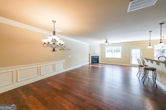 unfurnished living room with ceiling fan with notable chandelier, ornamental molding, and dark hardwood / wood-style floors