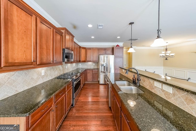 kitchen featuring stainless steel appliances, sink, hanging light fixtures, and dark stone counters