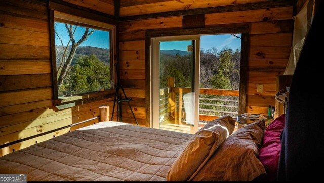 bedroom featuring multiple windows, a mountain view, and wooden walls