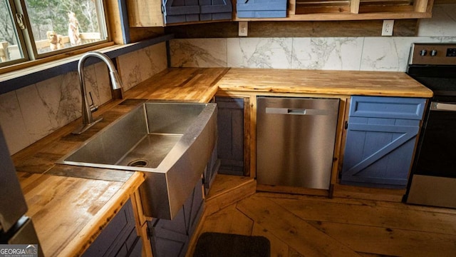 kitchen featuring stainless steel appliances, sink, butcher block countertops, and decorative backsplash