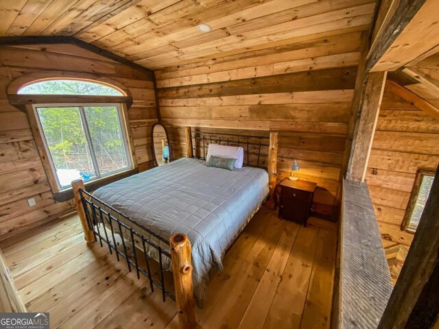 unfurnished bedroom featuring vaulted ceiling, wooden walls, wood ceiling, and light hardwood / wood-style flooring