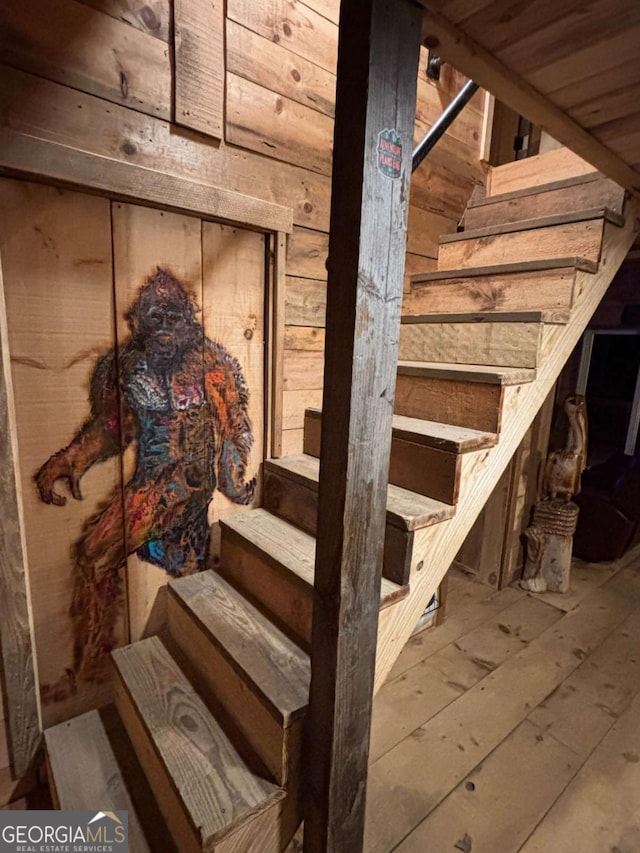 stairway featuring hardwood / wood-style flooring and wood walls