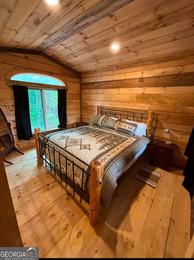 bedroom with light hardwood / wood-style flooring, wooden walls, wooden ceiling, and vaulted ceiling