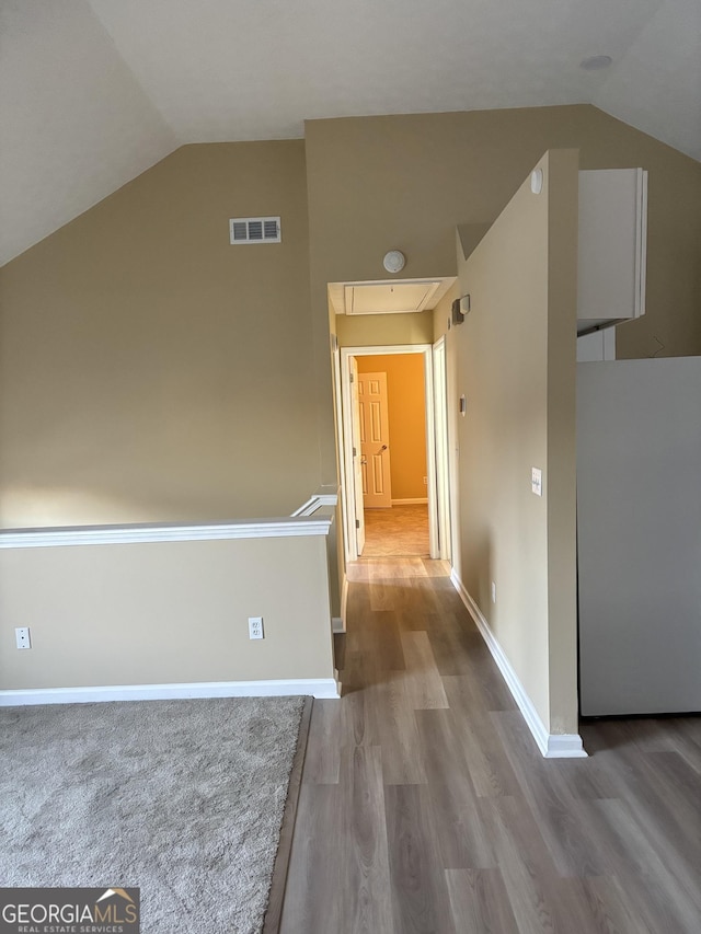 hall with vaulted ceiling and wood-type flooring