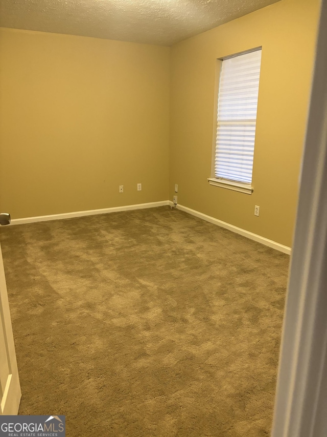 carpeted empty room featuring a textured ceiling