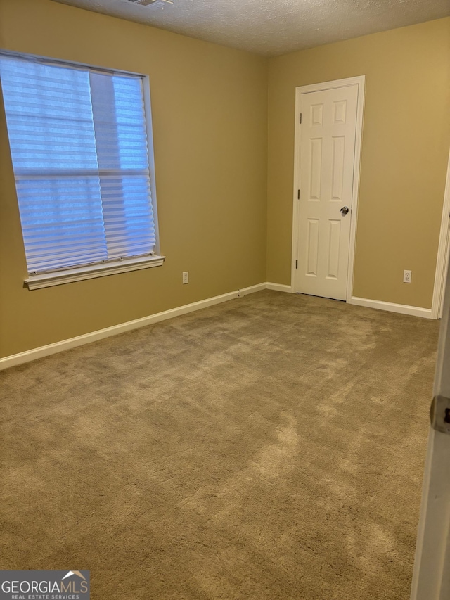 carpeted empty room featuring a textured ceiling