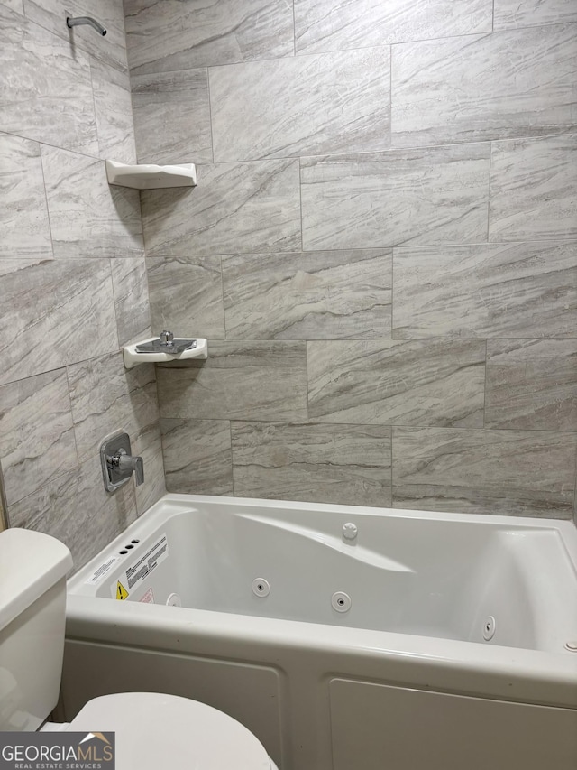 bathroom featuring tiled shower / bath and toilet