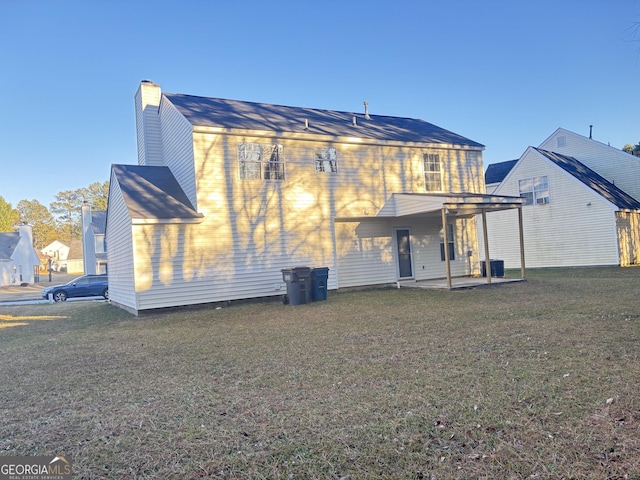 rear view of property with a patio and a lawn