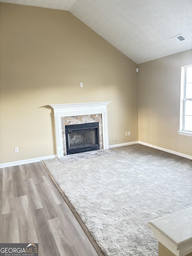 unfurnished living room with hardwood / wood-style flooring, a premium fireplace, and vaulted ceiling