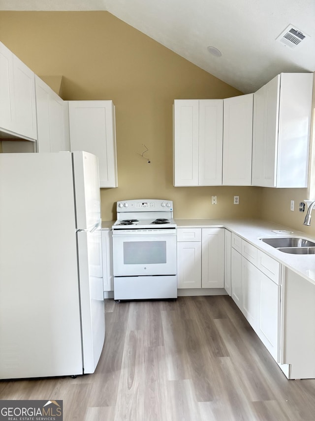 kitchen featuring sink, white cabinetry, vaulted ceiling, white appliances, and light hardwood / wood-style floors