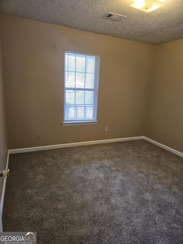 empty room with carpet and a textured ceiling